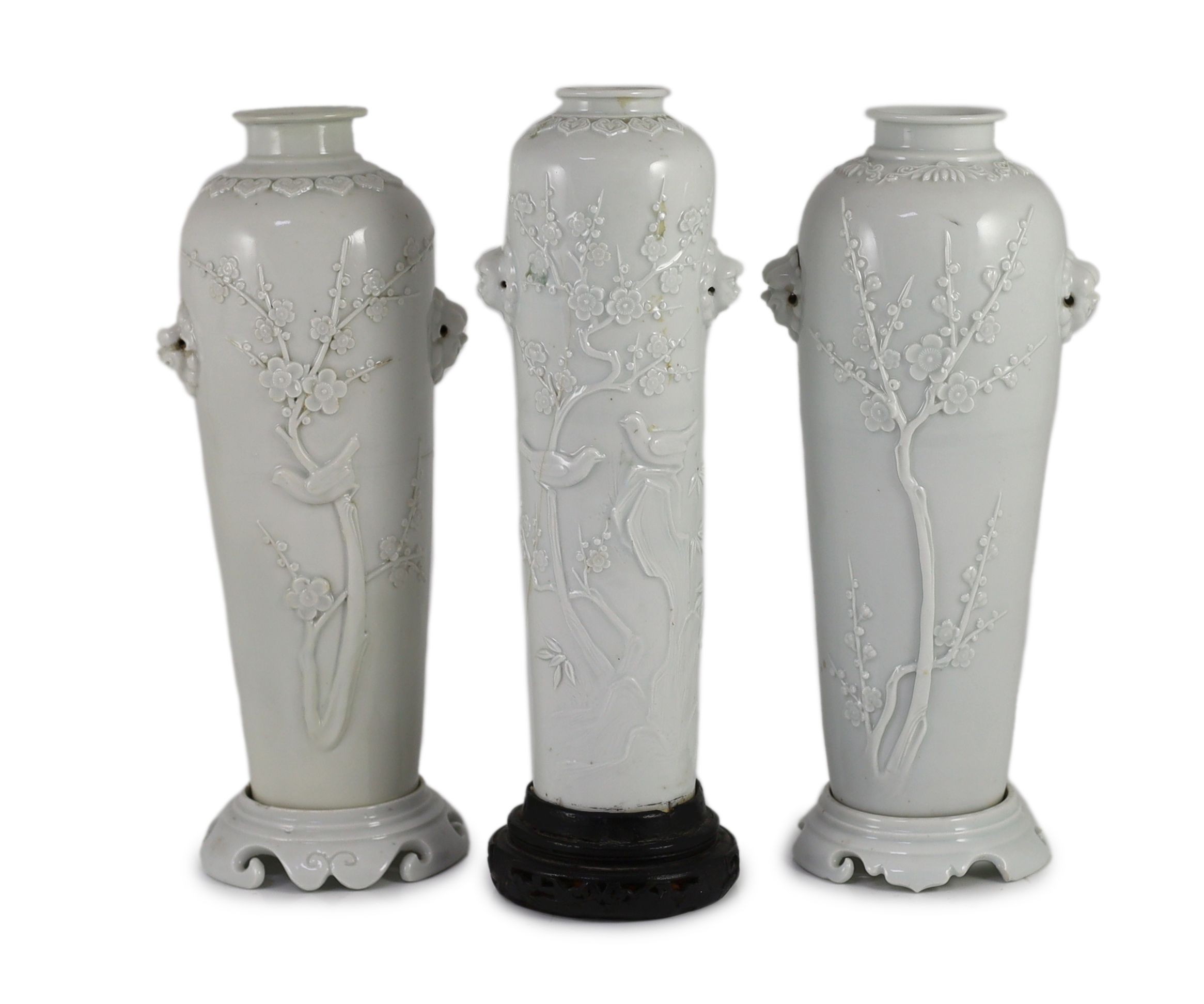 A near pair of Chinese blanc-de-chine sleeve vases with stands and a similar slender vase, Dehua kilns, 18th century Tallest 26cm high, damage